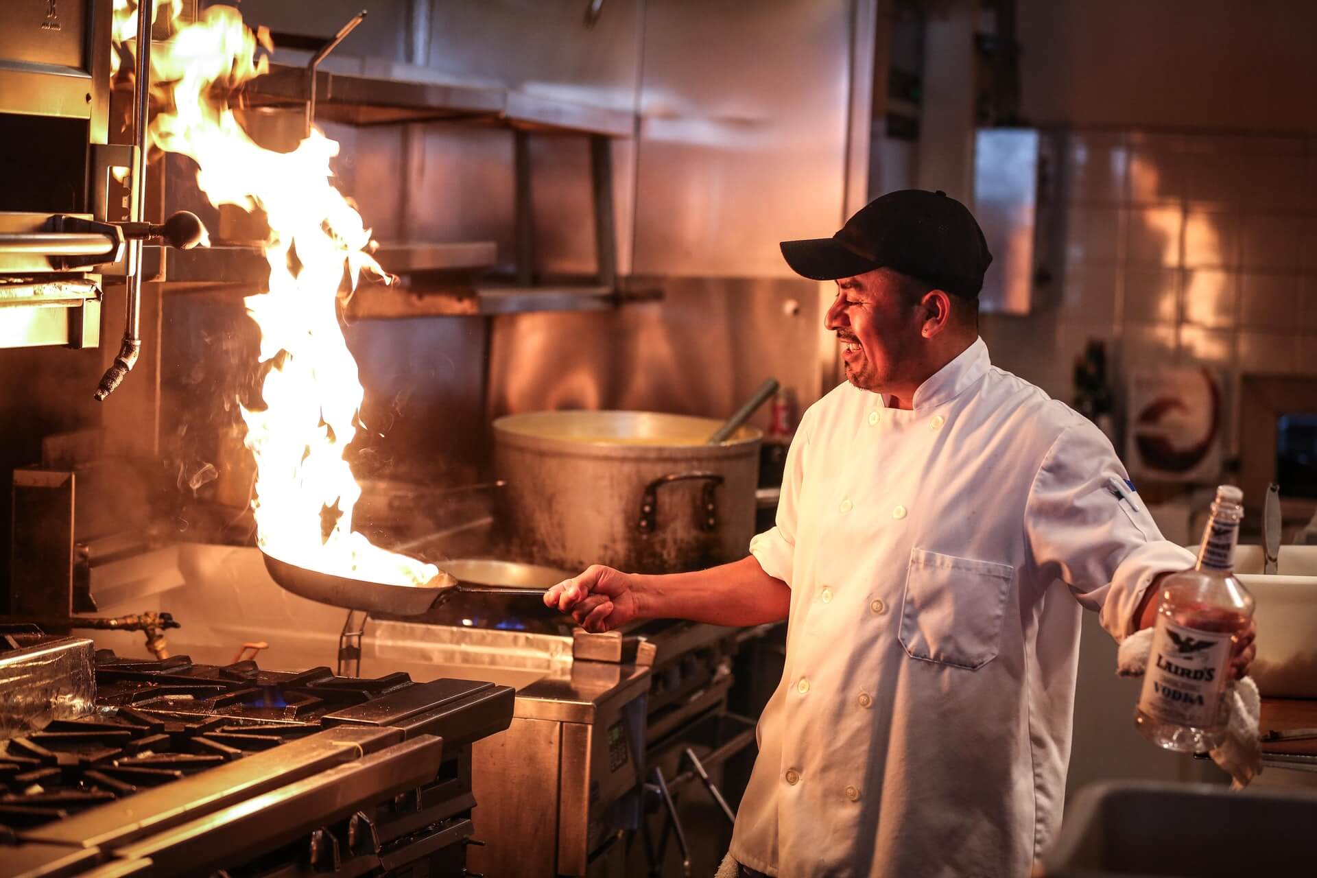 Chef in commercial kitchen with fire pan
