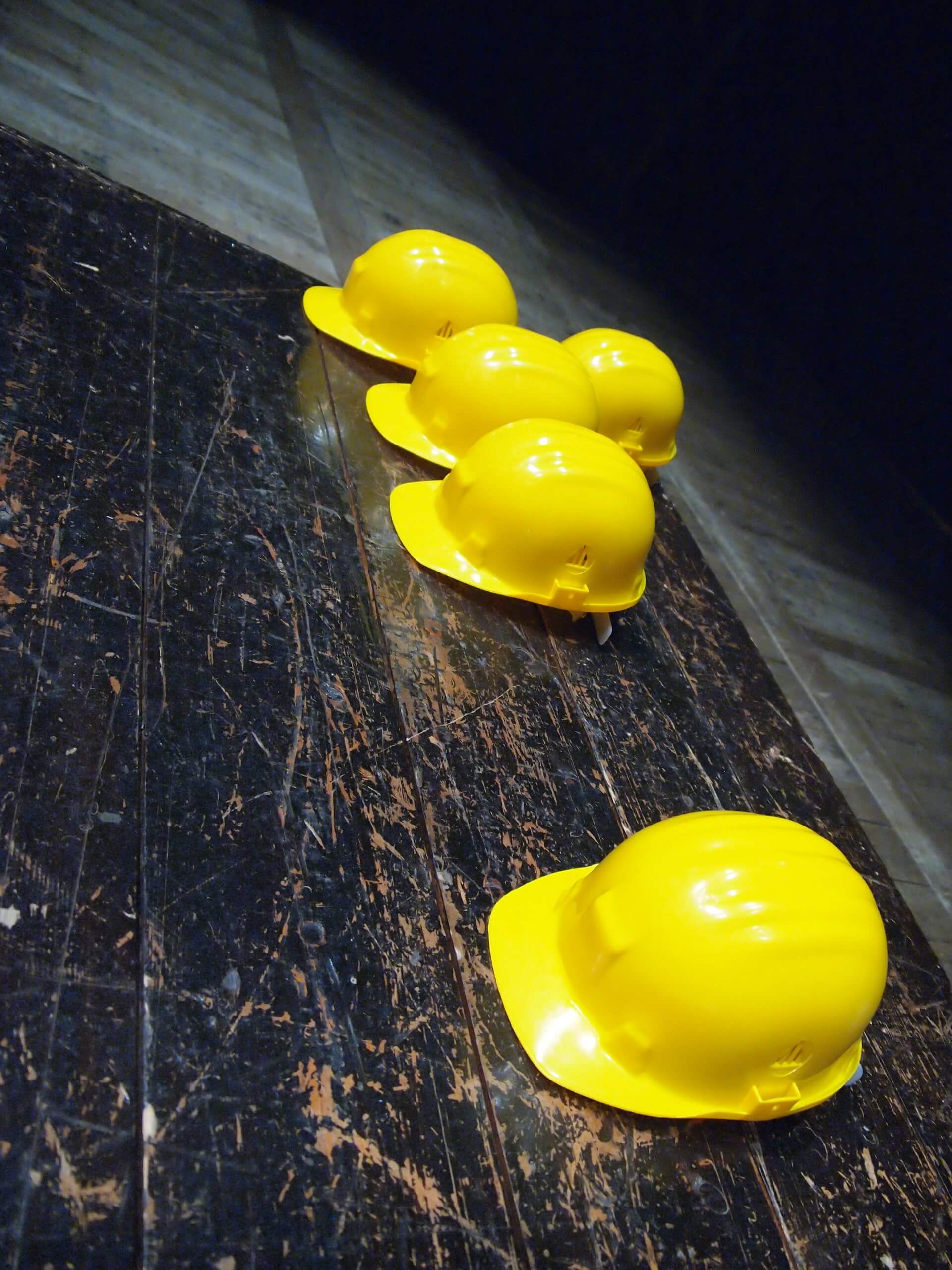 five yellow hard hats on a floor