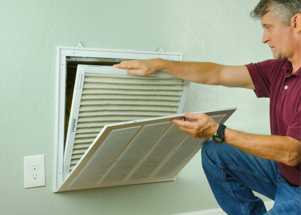 man changing air filter in home